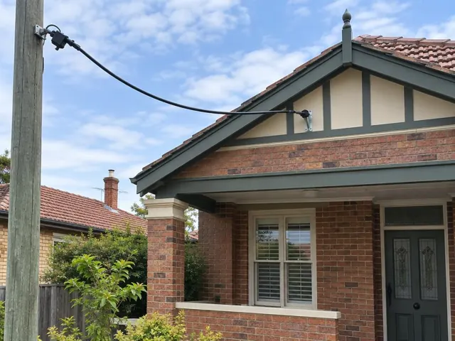Overhead service cable and bracket on a brick house exterior with tiled roof in Toronto