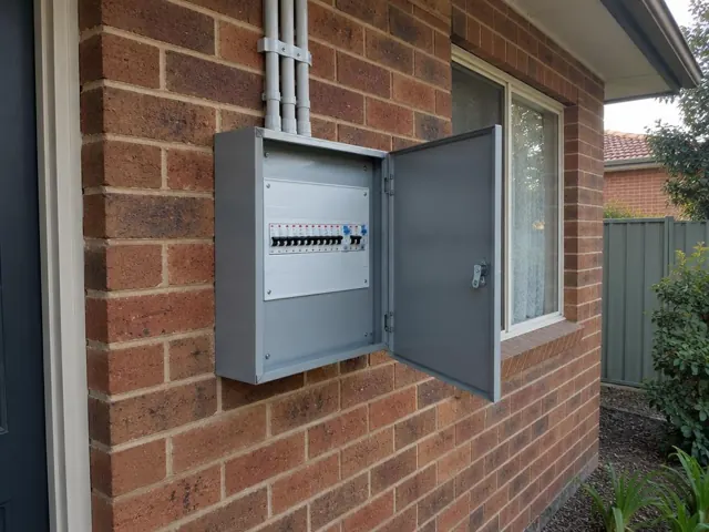 Open exterior switchboard on a brick wall beside a window in Blackalls Park